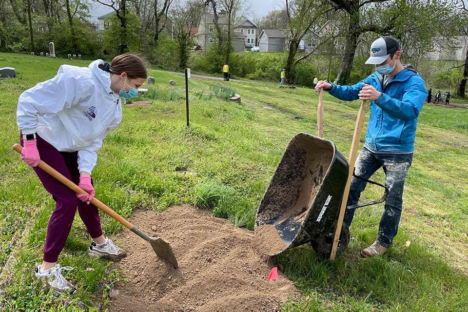 Students at the Chaifetz School's Day fo Service dump dirt from a wheel barrel to fill a holes at Hillsdale Cemetery in St. 路易.
