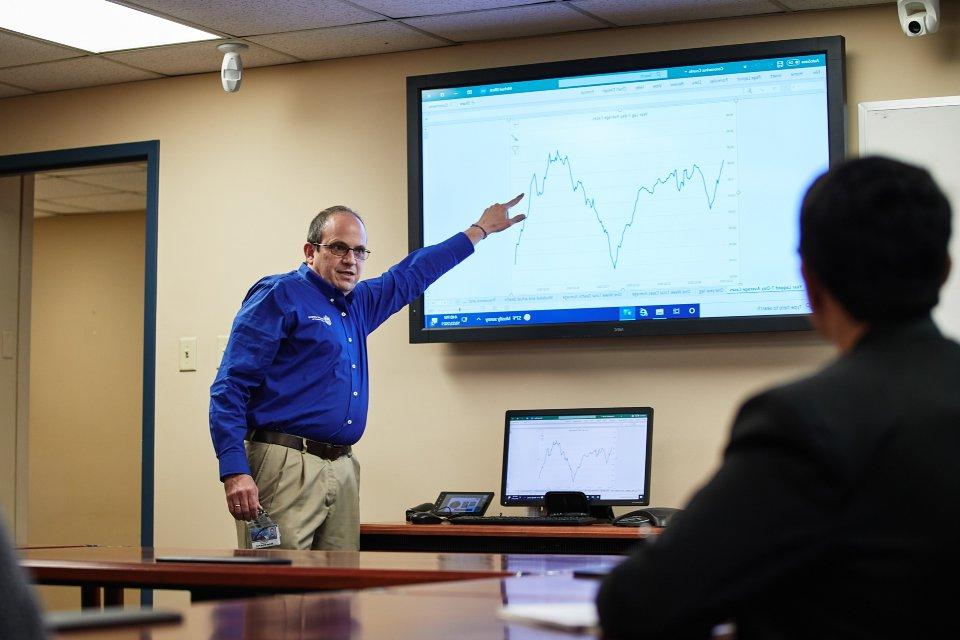 Michael Elliott, Ph.D., stands in the front of a conference room in a meeting, pointing at a screen with grahpical data.