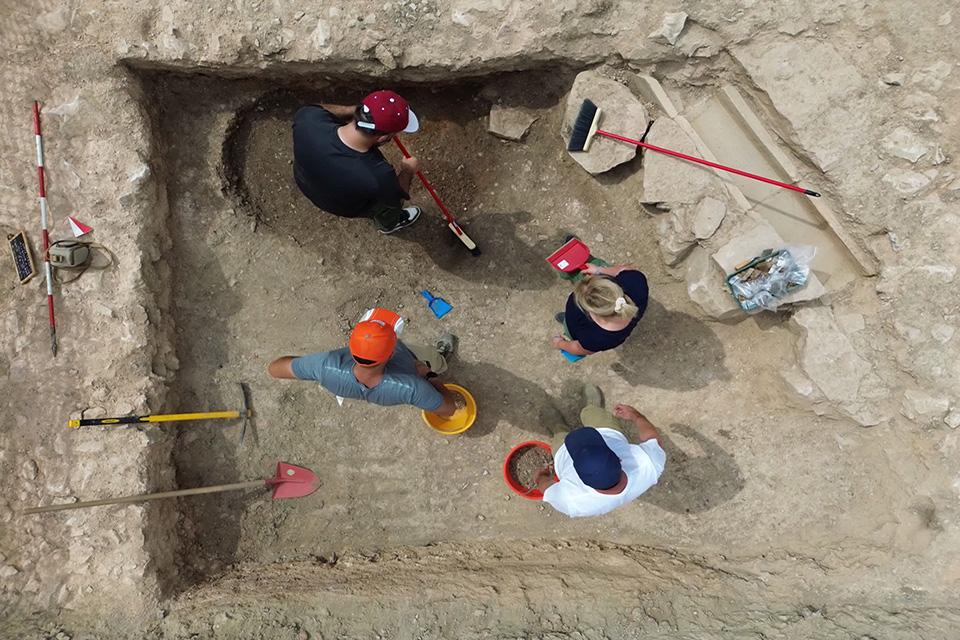 从上面可以看到挖掘机在工地上工作，有扫帚、铲子和水桶.