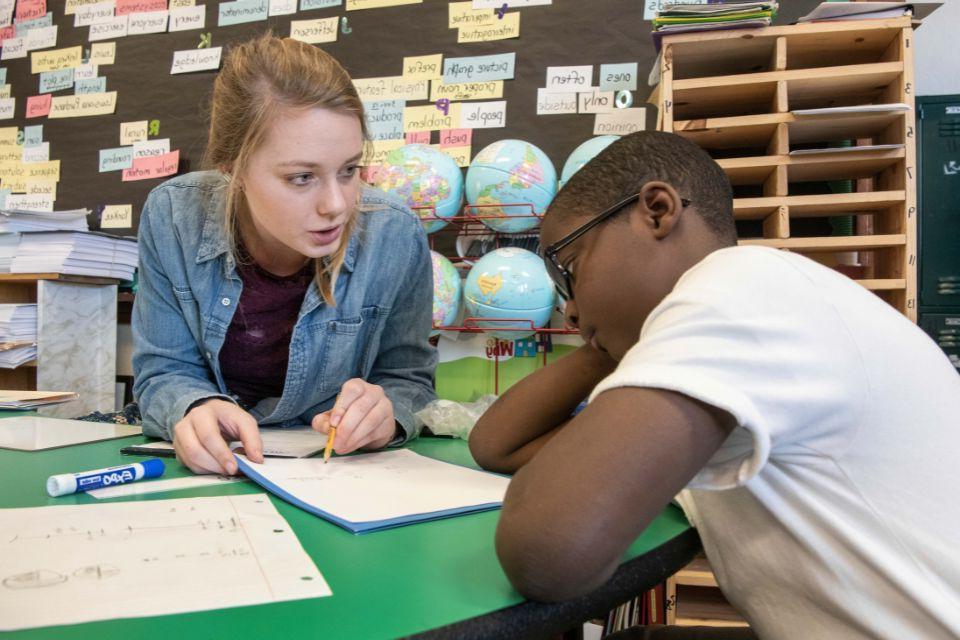 College student teaching an elementary school student in an elementary school classroom